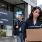 Canada Revenue Agency employee carrying a box of personal belongings outside a CRA office amid 2026 workforce cuts.